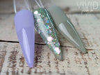 Three nail dip powder samples in purple, hazel green,  glittery, and gray on a wooden surface with 'Vivid Glam Co' branding.