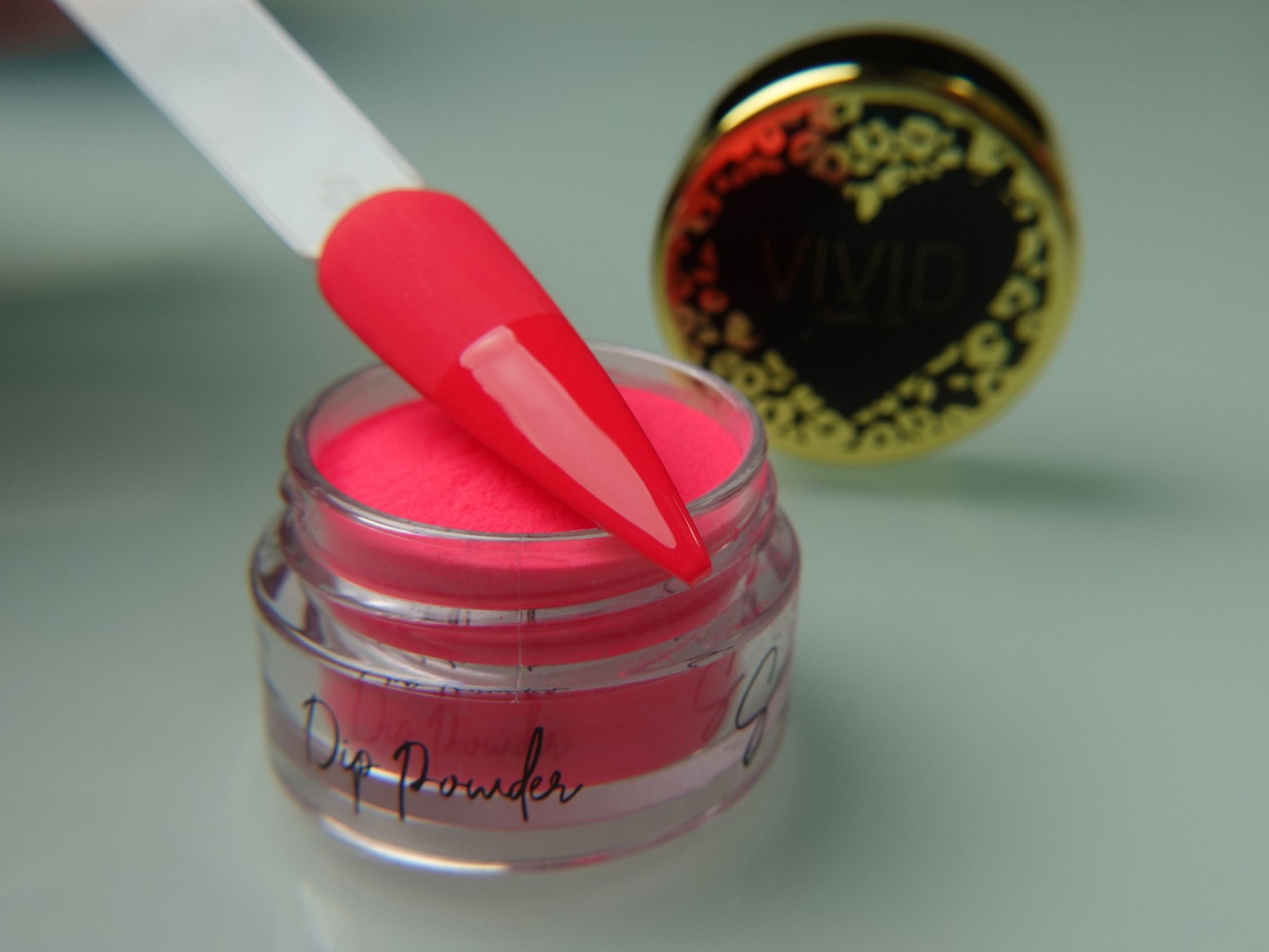 A collection of nail dip powder kit items including bottles of glue, activate, and gloss, a jar of dip powder, a nail tool kit with a file and brush, and additional replacement brush/cap.