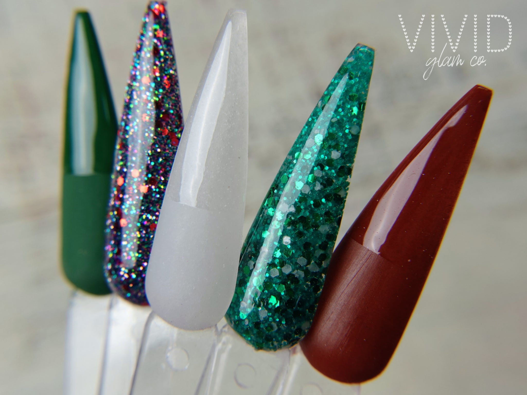 Set of long, colorful nails with glittery finishes on a neutral background.
