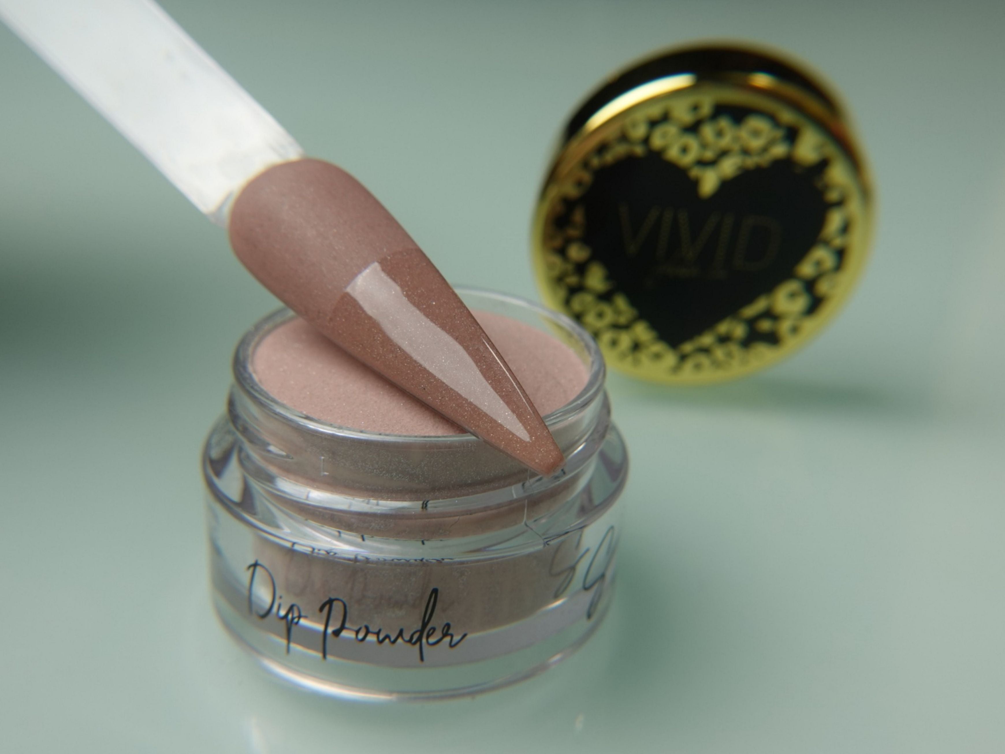 A collection of nail dip powder kit items including bottles of glue, activate, and gloss, a jar of dip powder, a nail tool kit with a file and brush, and additional replacement brush/cap.